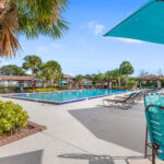 Apartments Near Rollins College - The Taylor - Pool with Umbrella Tables, Lounge Chairs, Surrounded by Palm Trees