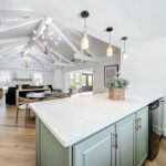 Clubhouse kitchen with island countertop, dishwasher, indoor dining seating and couches next to a fireplace
