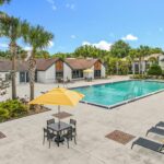One-BR Apartments in Winter Park, FL - The Taylor at Winter Park - Outdoor Swimming Pool Surrounded by Lounge Chairs and Umbrellas