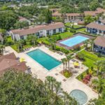 Exterior aerial shot of apartment buildings with pool, tennis court, and hot tub in the center